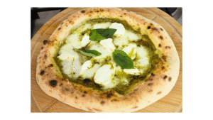 Homemade creamy pesto pizza with fresh mozzarella and a golden-brown crust